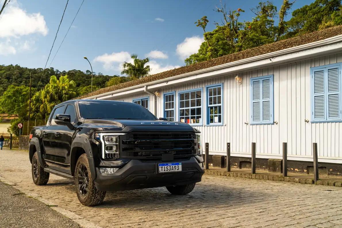 Tunland V7 preta estacionada diante de casa de madeira